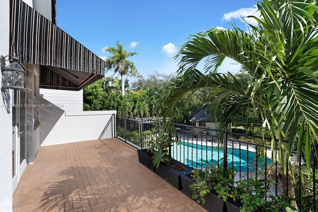 view of patio featuring a fenced in pool and a balcony