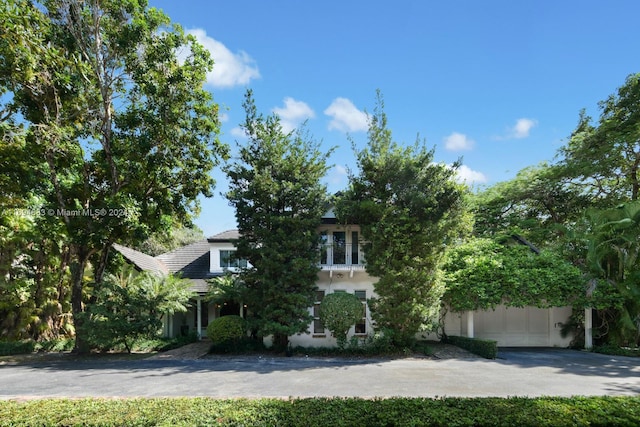 view of property hidden behind natural elements featuring a garage