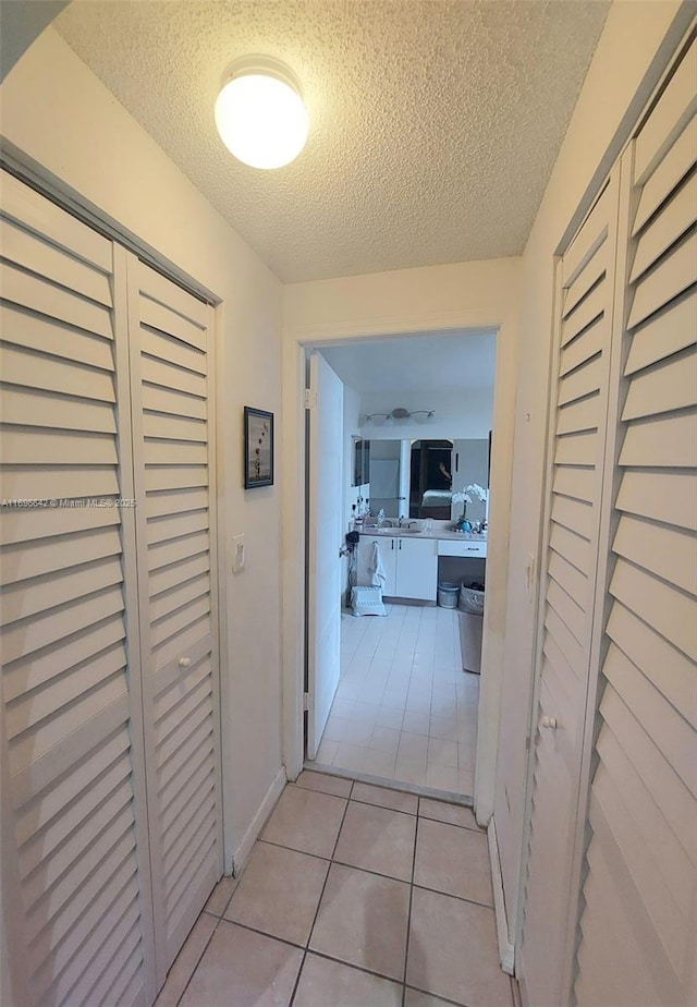 hall with light tile patterned floors and a textured ceiling