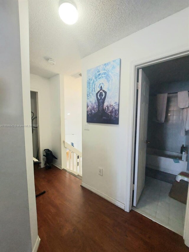 hallway with dark hardwood / wood-style flooring and a textured ceiling