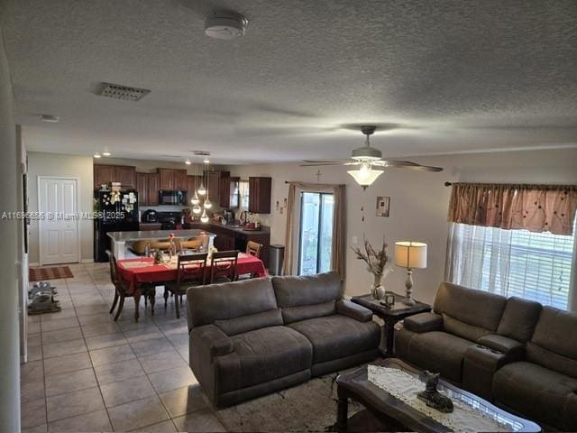 living room featuring light tile patterned floors, a ceiling fan, and a textured ceiling