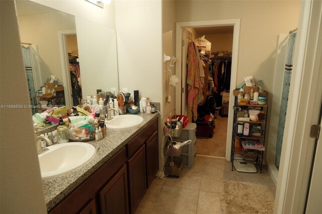 full bath featuring a walk in closet, double vanity, a sink, and tile patterned floors