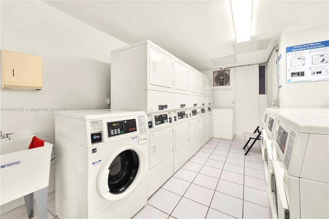 common laundry area with light tile patterned floors, washer and clothes dryer, a sink, and stacked washer / drying machine