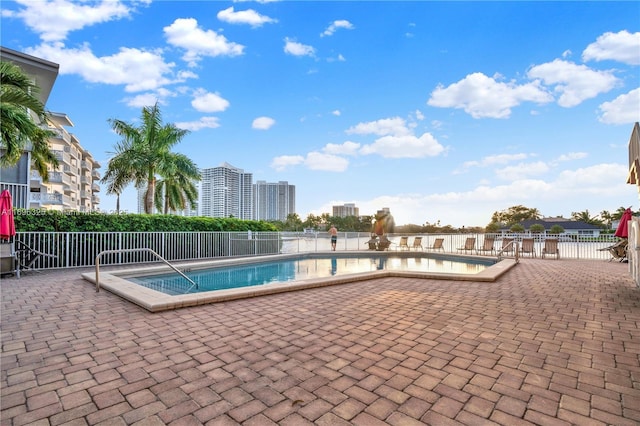 pool with a view of city, a patio, and fence