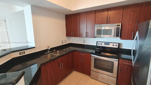 kitchen featuring light tile patterned flooring, sink, stainless steel appliances, and dark stone counters