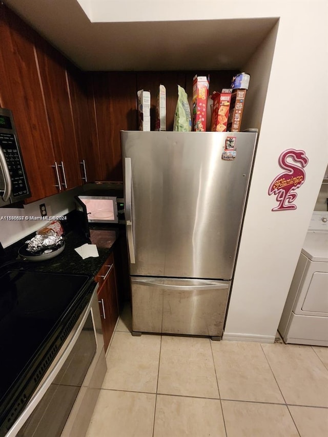 kitchen featuring appliances with stainless steel finishes, light tile patterned floors, dark brown cabinets, and washer / dryer