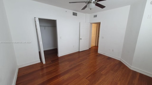 unfurnished bedroom with a closet, dark hardwood / wood-style floors, a spacious closet, and ceiling fan