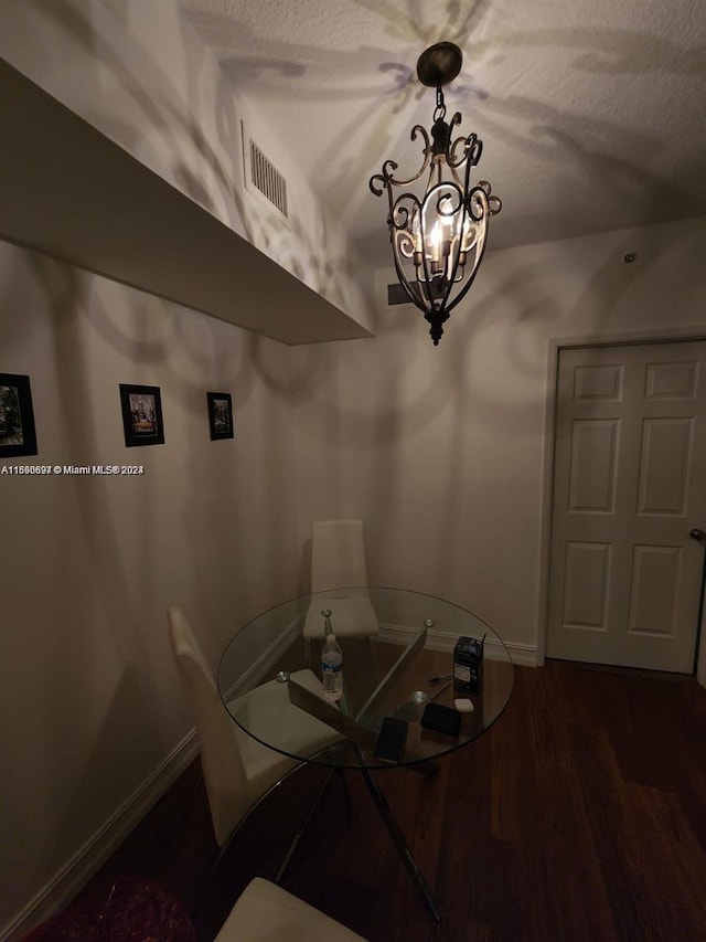 unfurnished dining area featuring lofted ceiling, a textured ceiling, dark wood-type flooring, and a notable chandelier