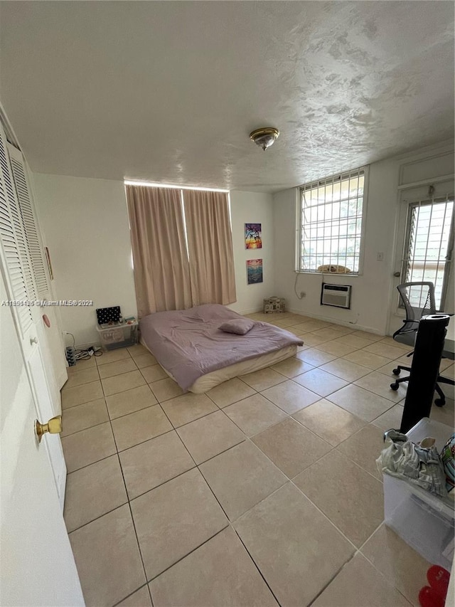 unfurnished bedroom featuring a wall mounted air conditioner, light tile patterned floors, and a closet