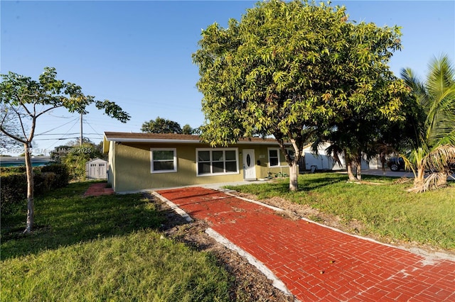 view of front of home featuring a front yard, stucco siding, an outdoor structure, and a storage unit