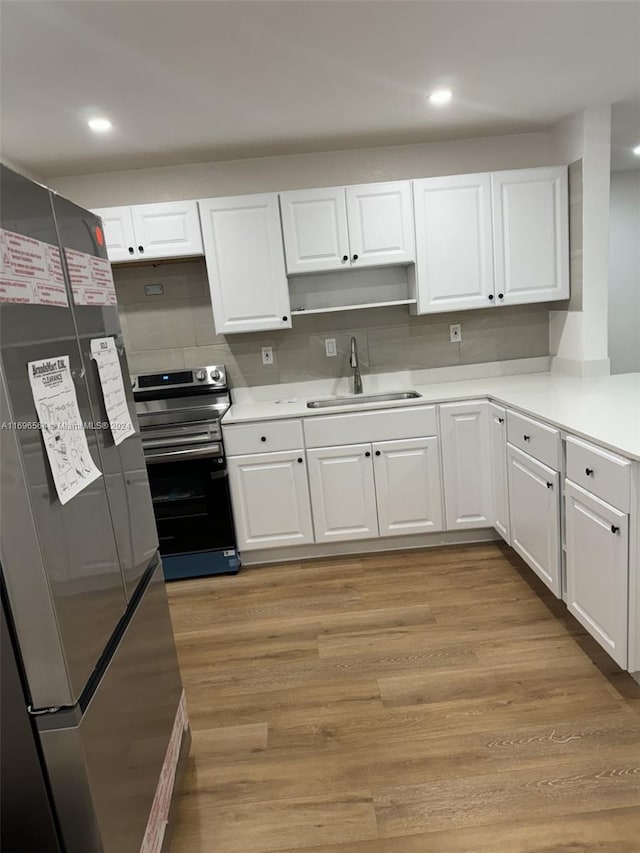 kitchen featuring white cabinetry, sink, light hardwood / wood-style flooring, decorative backsplash, and appliances with stainless steel finishes