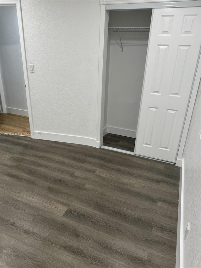 unfurnished bedroom featuring a closet and dark wood-type flooring