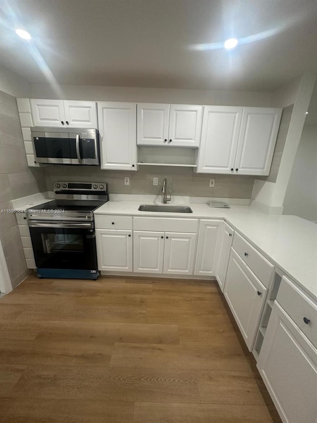 kitchen featuring tasteful backsplash, stainless steel appliances, sink, white cabinets, and light hardwood / wood-style floors