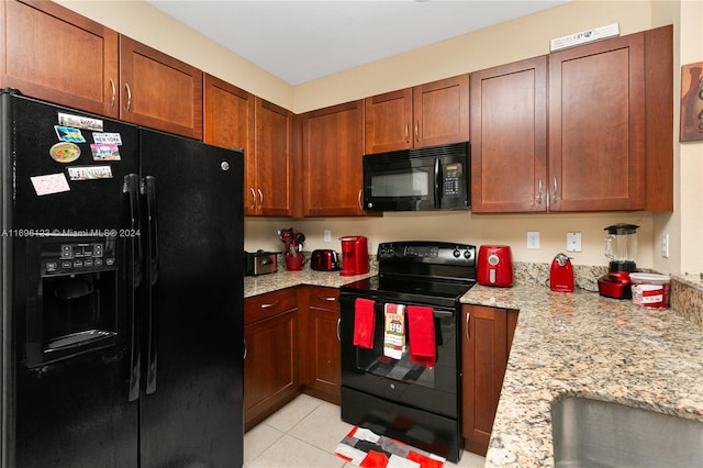 kitchen with light stone countertops, light tile patterned flooring, and black appliances