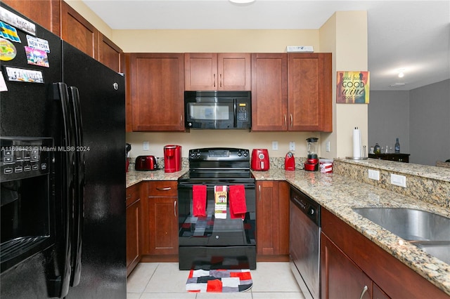 kitchen with kitchen peninsula, light stone countertops, light tile patterned floors, and black appliances