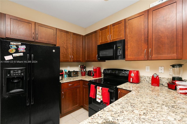 kitchen featuring light stone counters, light tile patterned floors, and black appliances