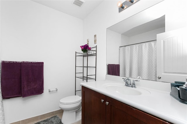 bathroom with toilet, vanity, and tile patterned floors