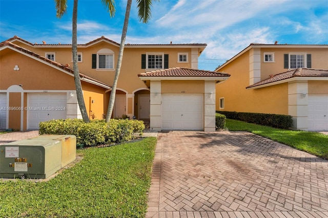 mediterranean / spanish-style house with a garage and a front lawn