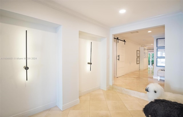 hall with a barn door, ornamental molding, and light tile patterned flooring