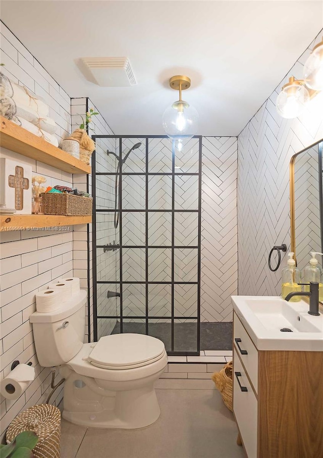 bathroom with tile patterned floors, an enclosed shower, toilet, vanity, and tile walls