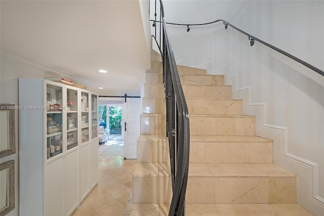 stairs with a barn door and crown molding