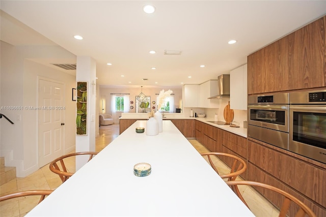 kitchen featuring stainless steel oven, black electric cooktop, white cabinetry, and wall chimney range hood