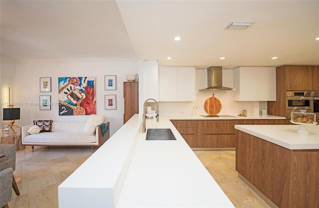 kitchen with ornamental molding, double oven, sink, wall chimney range hood, and white cabinetry