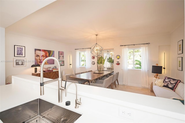 kitchen with ornamental molding, decorative light fixtures, a notable chandelier, and sink