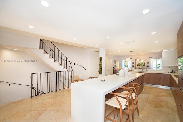 kitchen with a breakfast bar, a center island, white cabinetry, and sink