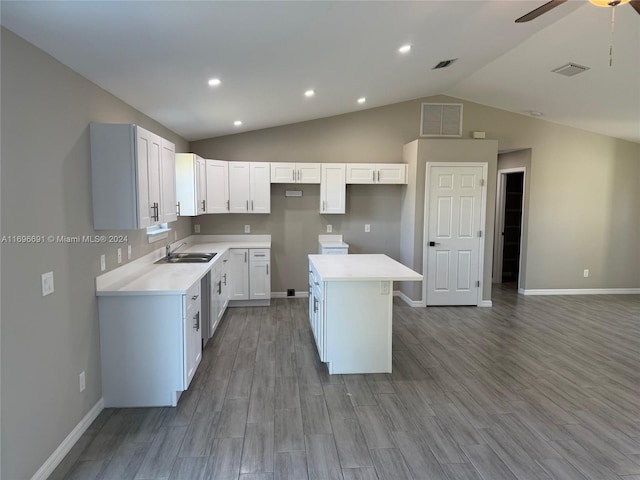 kitchen with vaulted ceiling, white cabinetry, a kitchen island, and light hardwood / wood-style flooring