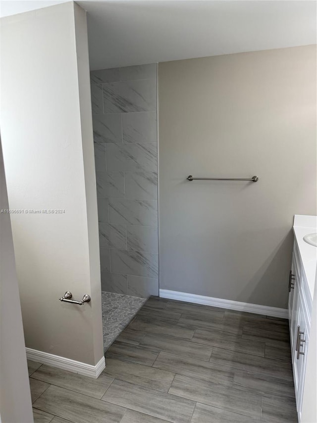 bathroom with tiled shower and vanity