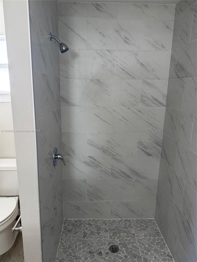 bathroom featuring a tile shower and toilet