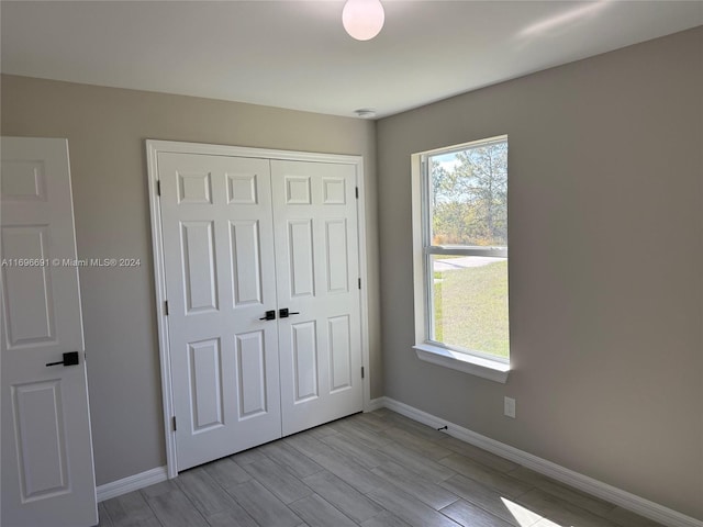 unfurnished bedroom with light wood-type flooring and a closet