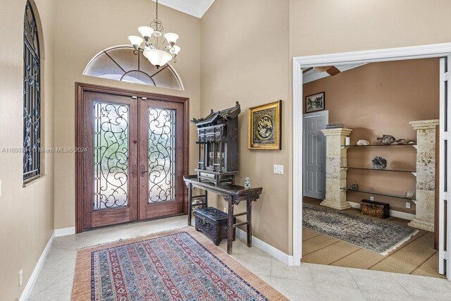 tiled entrance foyer with french doors, an inviting chandelier, and a high ceiling