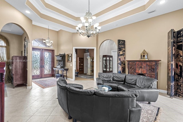 living room featuring a chandelier, a raised ceiling, crown molding, and french doors