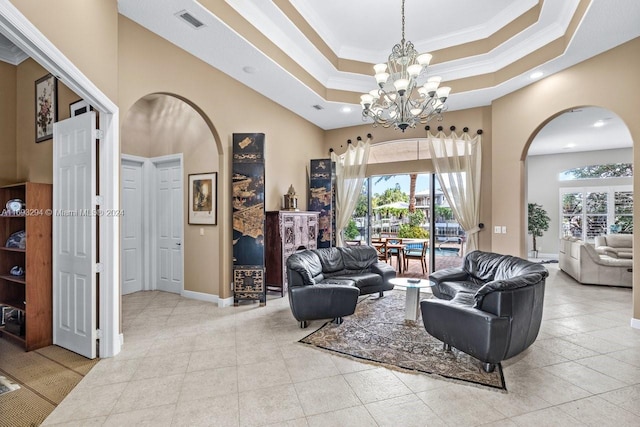 living room with a high ceiling, a raised ceiling, crown molding, light tile patterned floors, and a chandelier