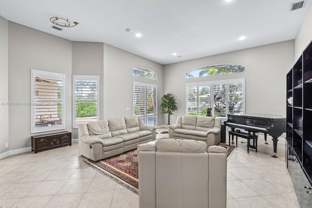 living room with a wealth of natural light, a towering ceiling, and light tile patterned floors