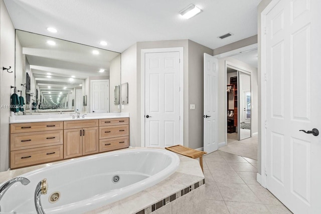 bathroom featuring tile patterned flooring, vanity, and tiled tub