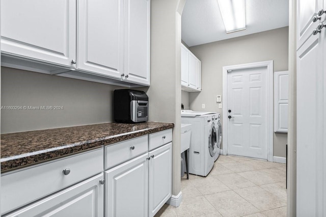 laundry room featuring washer and dryer, cabinets, and light tile patterned floors