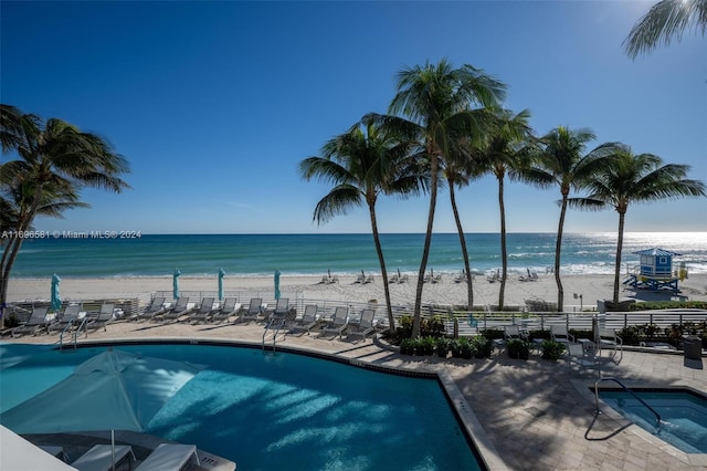 view of pool with a patio area, a water view, and a beach view