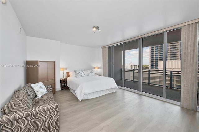 bedroom featuring hardwood / wood-style flooring, expansive windows, and access to outside