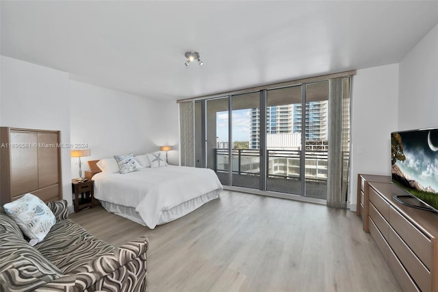 bedroom featuring access to outside, a wall of windows, and light wood-type flooring