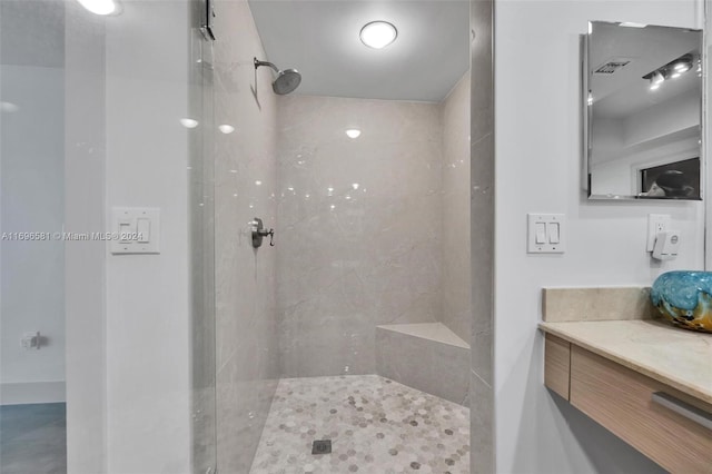 bathroom featuring tiled shower and vanity