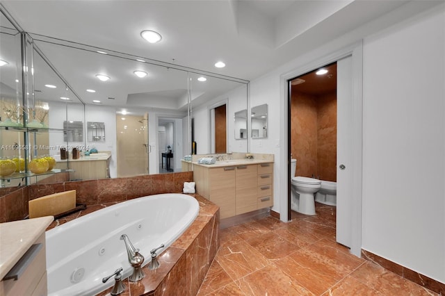 bathroom featuring vanity, a relaxing tiled tub, and toilet