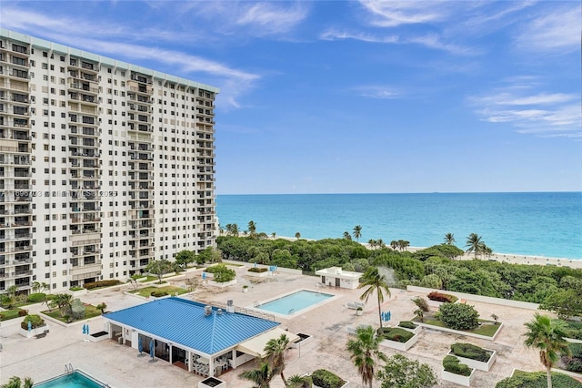 view of pool featuring a water view, a patio area, and a beach view