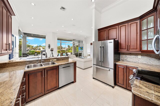 kitchen with light stone countertops, sink, crown molding, decorative backsplash, and appliances with stainless steel finishes