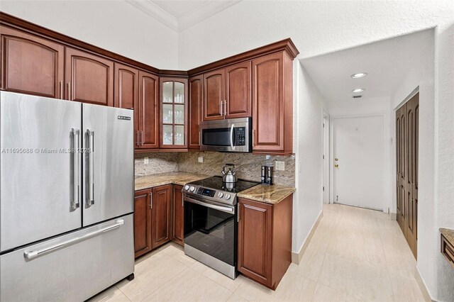 kitchen featuring appliances with stainless steel finishes, tasteful backsplash, light stone counters, ornamental molding, and light tile patterned floors