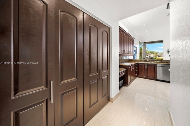 kitchen with light tile patterned floors, ornamental molding, a sink, dark brown cabinets, and dishwasher