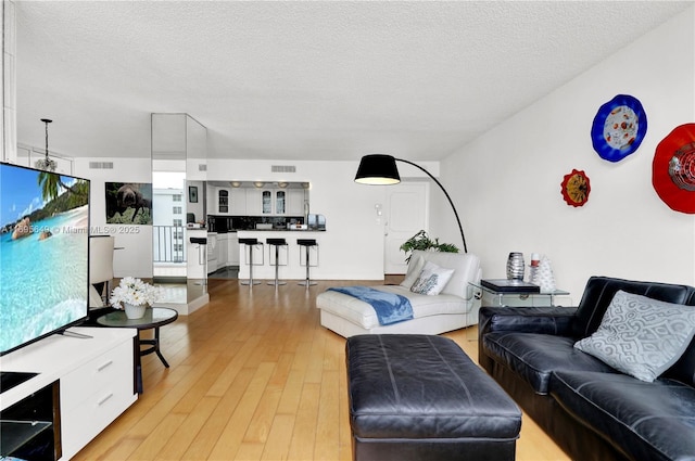 living room featuring a textured ceiling and light wood-type flooring