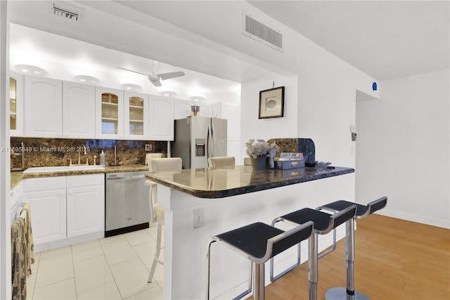 kitchen featuring white cabinetry, a breakfast bar area, stainless steel appliances, and tasteful backsplash